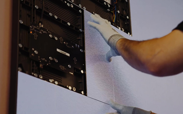 White gloved man’s arm fixes LED pixel cards in place